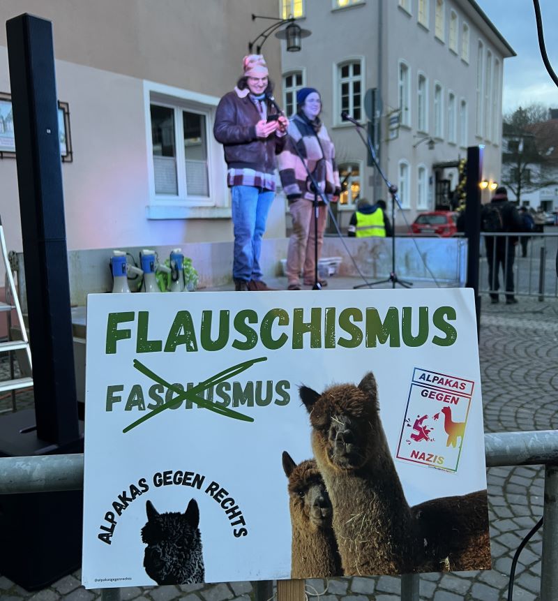 Im Hintergrund Jan & Astrid bei der Eröffnung der Kundgebung. Im Vordergrund unser Demoplakat "Flauschismus statt Faschismus". Foto von F4F